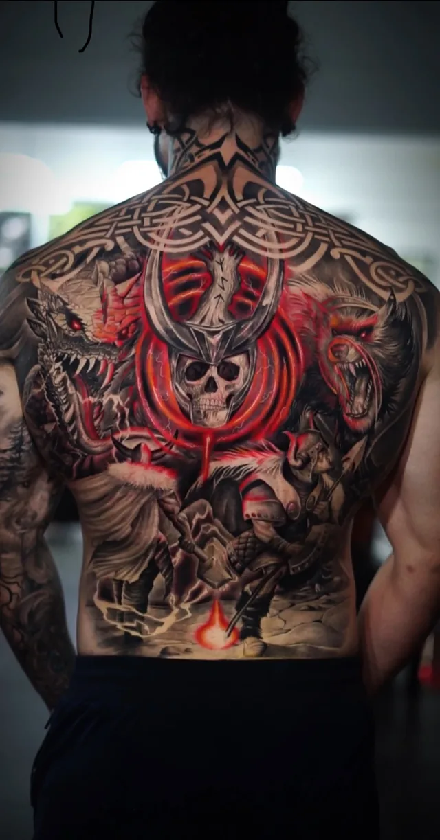 Full back tattoo of Norse warriors, a horned skull, dragon and wolf with red glowing accents