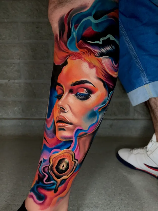 Color realism shin and calf tattoo of a woman's portrait surrounded by stylized smoke and a surreal eye