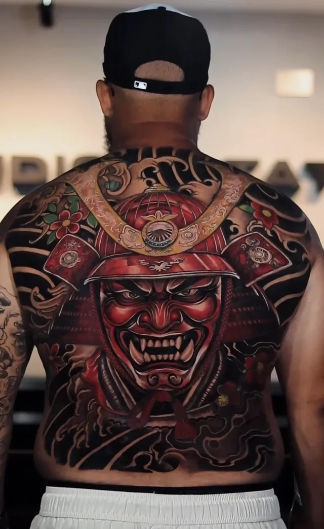 Full back color Japanese tattoo of a red samurai mask and ornate kabuto helmet framed by cherry blossoms