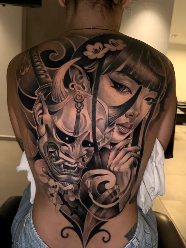 Full back black and grey Japanese tattoo of a geisha with a hannya mask, katana and cherry blossoms
